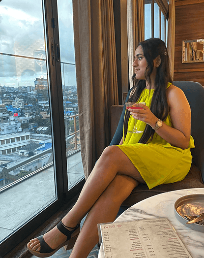Woman in yellow dress sitting by a window with city view