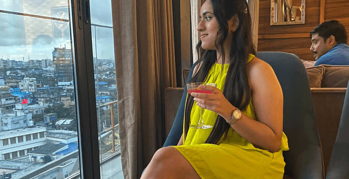 Woman in yellow dress sitting by a window with city view